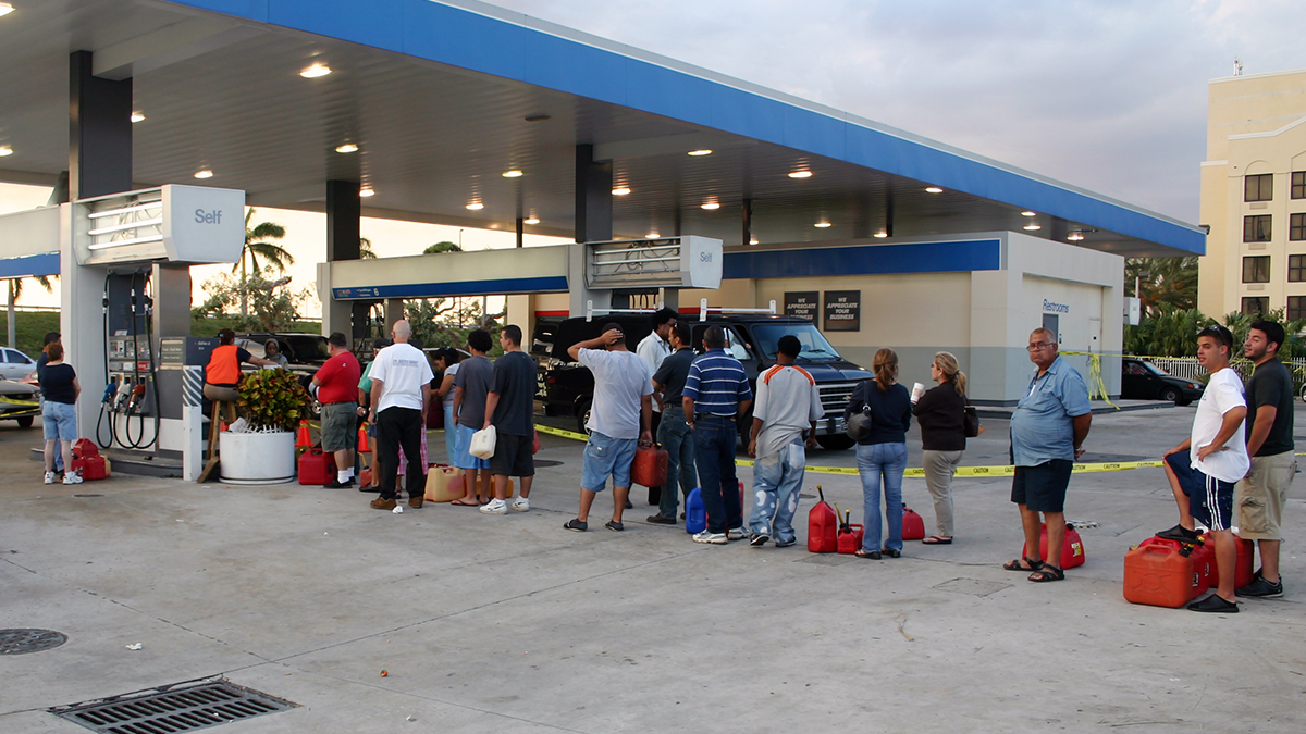 People with empty containers wait in line to buy gasoline
