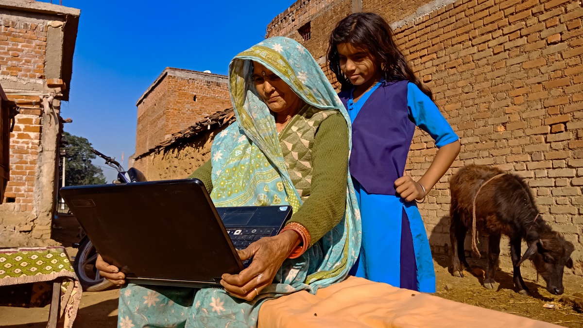 A women shows a young girl how to use a computer in a village in India.