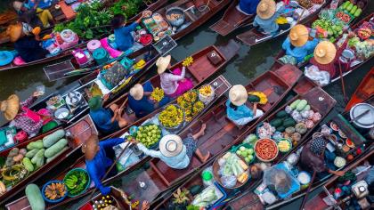 People transport fruits and vegetables in small boats in a country in Asia