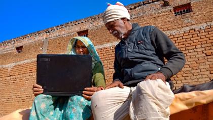 In an Indian village, a woman and man work on a laptop