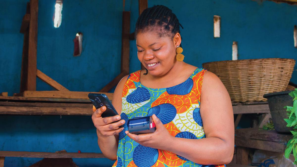 An African woman entrepreneur uses a digital payment device.