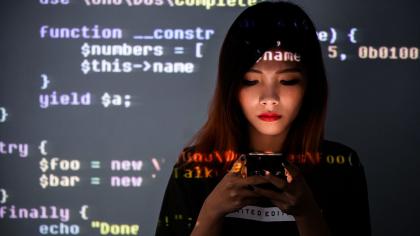 Woman on a phone with code behind her